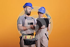 Professional builders in studio holding laptop