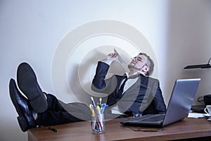 Professional burnout, laziness, unwillingness to work. Slacker businessman sitting in office with legs on the table and playing photo