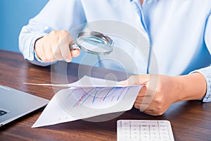 professional business woman hand holding and using magnifying glass search finance document paper on desk in office, businesswoman