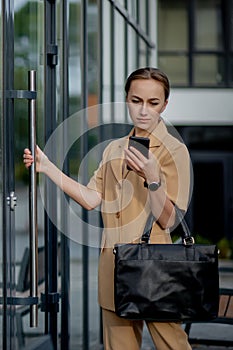 Professional business woman using mobile phone outdoors. Female texting on smart phone while walking outdoor in city