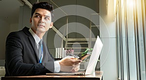 Professional Businessman By Window Working On Laptop In Coffee Shop