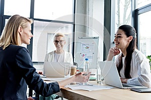 professional businesswomen smiling each other while working together