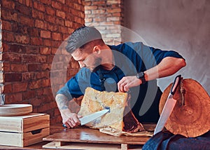 Professional butcher is cutting raw smoked meat on a table for c