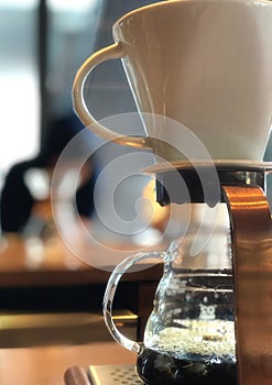 Professional cafe preparing coffee using chemex pour over coffee maker and drip kettle on wooden bar counter..dripping coffee