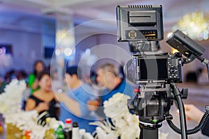 A professional camera on the blurred background of a banquet hall.