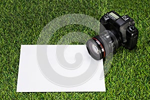 Professional camera with sheet of paper lying on the grass