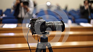 A professional camera on a tripod set up in front of a press conference. generative ai.