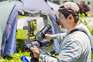 A professional cameraman prepares a camera and a tripod before shooting