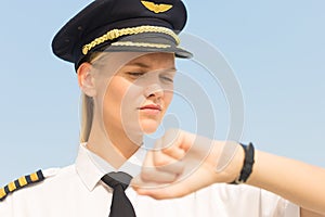 Professional captain pilot checking the time on her watch at the airport. Delay flight. Punctuality