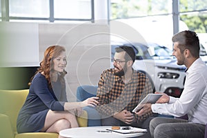 Professional car dealer offering luxurious vehicles during meeting with buyers in salon