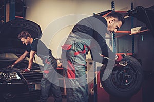 Professional car mechanic balancing car wheel on balancer in auto repair service.