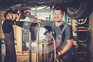 Professional car mechanic changing motor oil in automobile engine at maintenance repair service station in a car workshop.