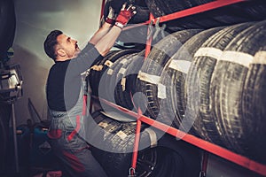 Professional car mechanic choosing new tire in auto repair service.