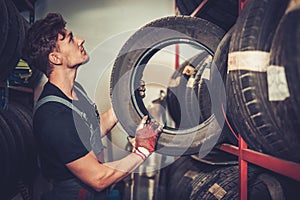 Professional car mechanic choosing new tire in auto repair service.