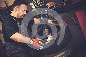 Professional car mechanic replace tire on wheel in auto repair photo
