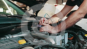 Professional car mechanic use electrician voltage multimeter, working in auto repair service. Regular preventative car