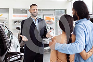 Professional Car Salesman Presenting Vehicle Options to Prospective Buyers