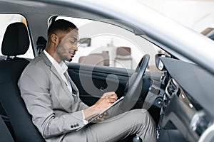 Professional Car Seller Sitting In Auto Taking Notes In Dealership