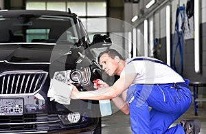 Professional car wash - worker in a car dealership polishes the