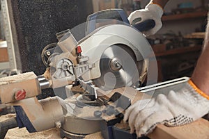 Professional carpenter cutting planks with sawmill in workshop, closeup