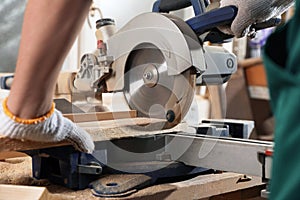 Professional carpenter cutting planks with sawmill in workshop, closeup