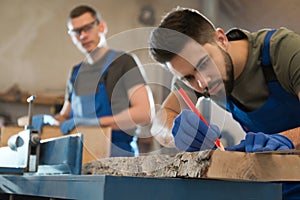 Professional carpenter making mark on board in workshop