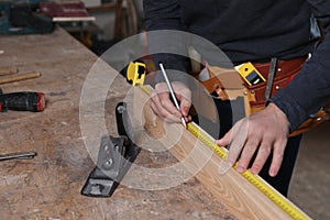 Professional carpenter measuring wooden plank at workbench