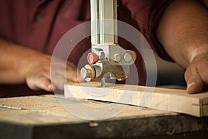 Professional carpenter working with sawing machine in workshop.