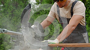 Professional carpenter works with a circular saw in the backyard