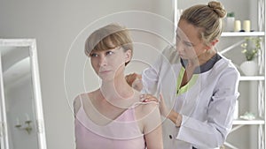 Professional Caucasian acupuncturist doing guasha massage for young beautiful woman. Portrait of female doctor massaging