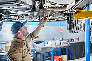 Professional Mechanic Performing Car Undercarriage Inspection photo