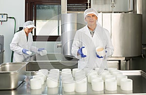 Professional cheesemaker working in shaping workshop of cheese factory