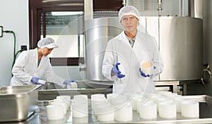 Professional cheesemaker working in shaping workshop of cheese factory