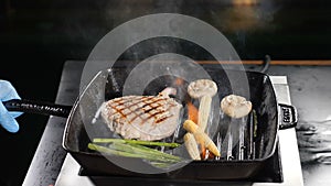 Professional chef cooking flambe style dish on restaurant kitchen. Igniting and stirring frying pan with flaming dish