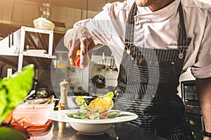 Professional chef cooking in the kitchen restaurant at the hotel, preparing dinner. A cook in an apron makes a salad of