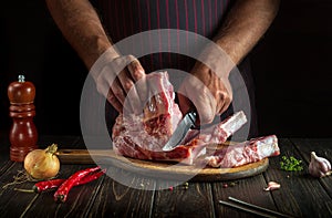 Professional chef cuts raw meat ribs on a cutting board before baking. Cooking delicious food in the kitchen. Delicious grill idea