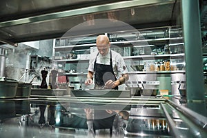 Professional chef. Famous young chef in black apron working at his modern restaurant kitchen