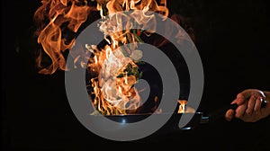 Professional chef and fire. Cooking vegetables and food over an open fire on a dark background. Hotel service photo background