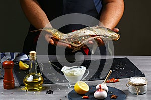 Professional chef and fish. Cooking fish on a dark background. Hotel service photo background. Horizontal view