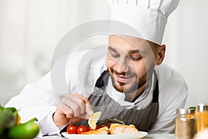 Professional Chef Guy Plating Salmon Dish Standing In Restaurant Kitchen