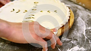 A professional chef pinches the edges of the pie.