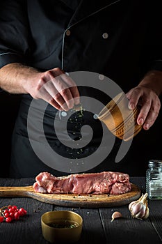 Professional chef prepares raw veal meat. Before baking, the chef adds a dry herbal seasoning to the beef. National dish is being
