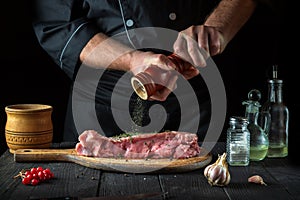 Professional chef prepares raw veal meat. Before baking, the chef adds pepper to the beef. National dish is being prepared in the