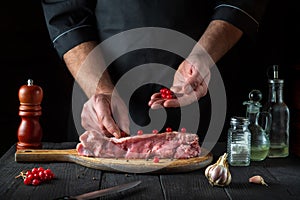 Professional chef prepares raw veal meat. Before baking, the cook puts the viburnum on the beef. National dish is being prepared
