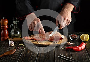 Professional chef prepares Sebastes fish. Preparing to cook fish food. The cook cuts with knife a red fish before roast