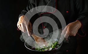 A professional chef prepares vegetables in a frying pan. The concept of cooking healthy vegetarian food and meals on a dark