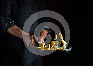 Professional chef prepares zucchini in a pan. Cooking vegetables healthy vegetarian food and meal on dark background