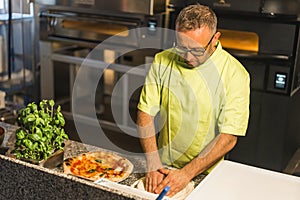 professional chef preparing pizza dough, an electric oven in the background