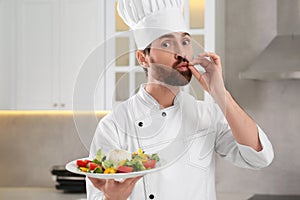 Professional chef presenting delicious salad in kitchen