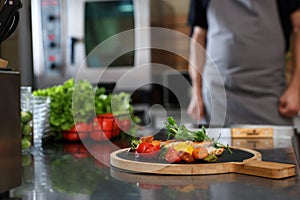 Professional chef in restaurant kitchen, focus on table with delicious grilled meat